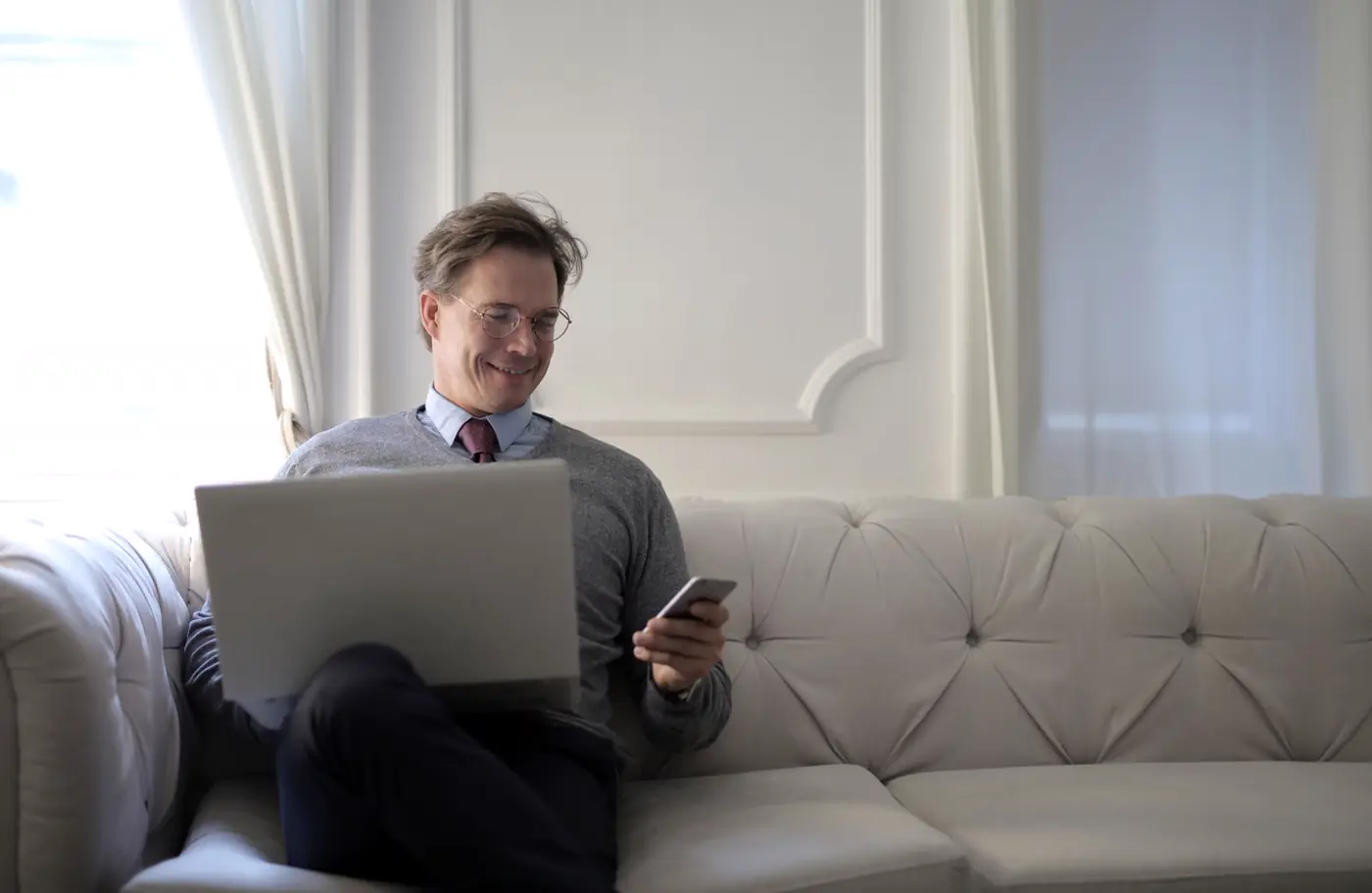 Professional checking email replies on a laptop and phone